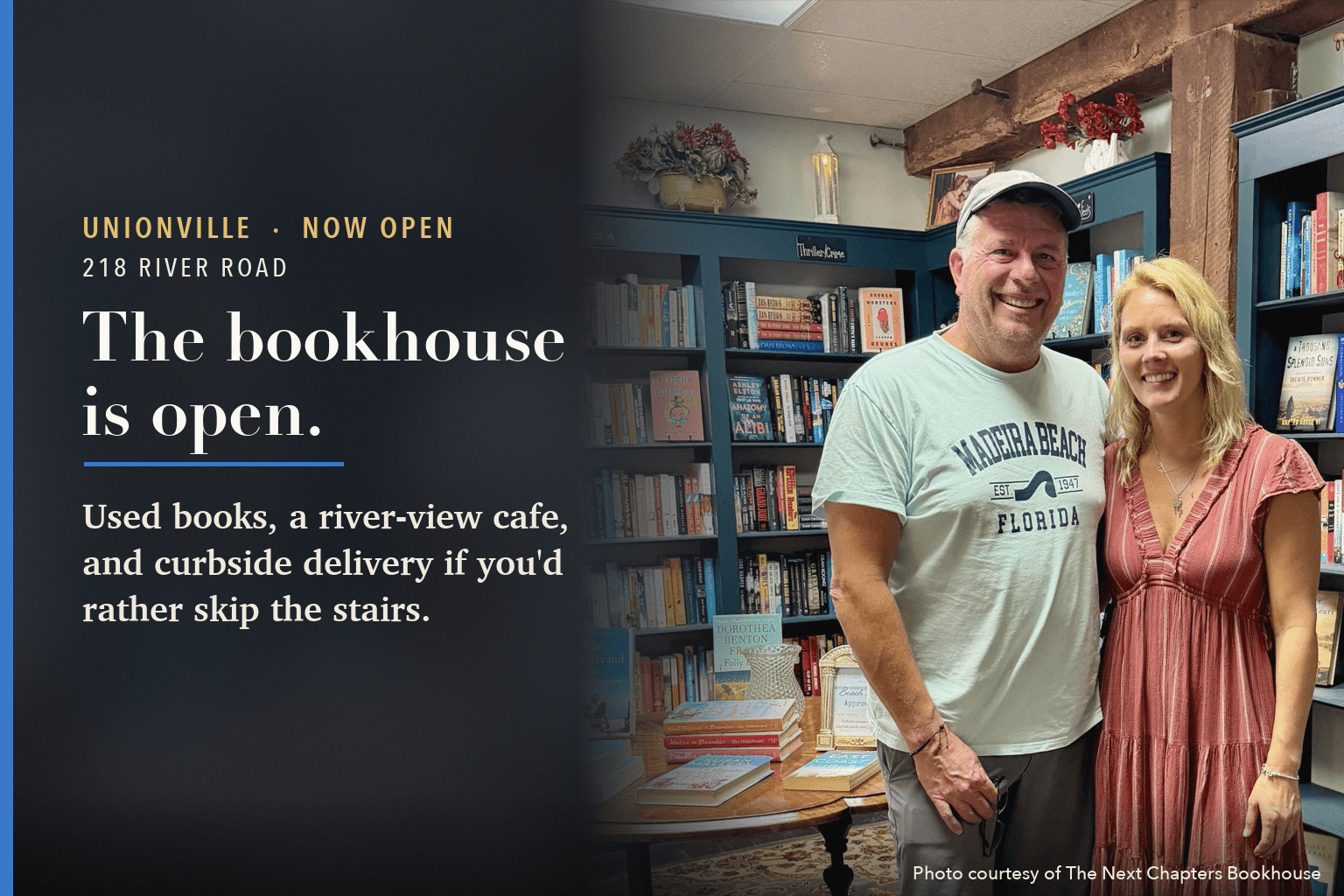 The two owners of The Next Chapters Bookhouse smile between teal bookshelves inside the shop, beside the words: The bookhouse is open. Used books, a river-view cafe, and curbside delivery if you'd rather skip the stairs.